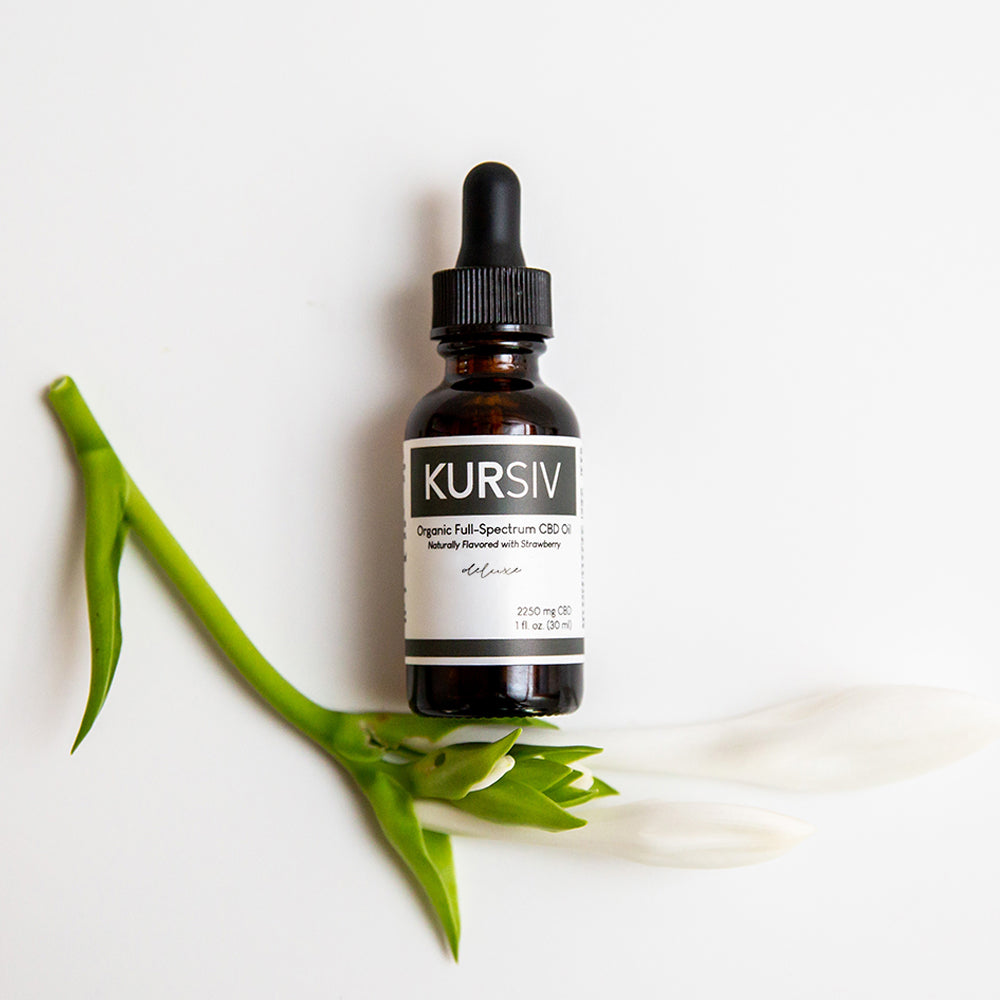 Kursiv deluxe lab certified CBD oil in bottle on white flower