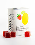 Tin of Kursiv Organics gummies with a white label on white background, red square gummies in the foreground.